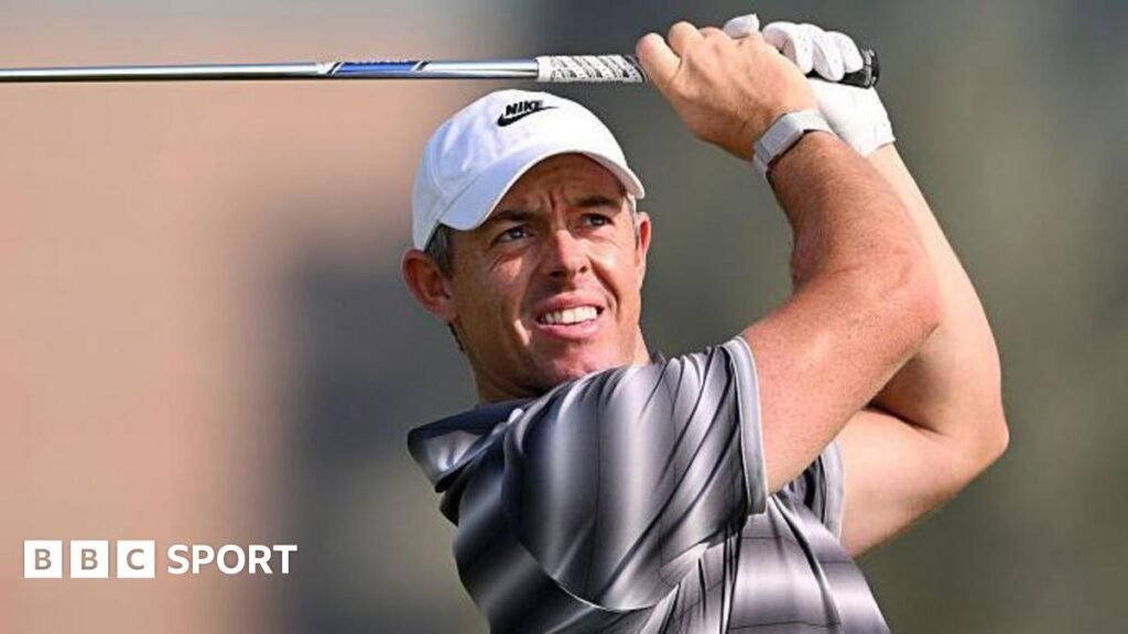 Rory McIlroy watches his shot as he holds a club above his head