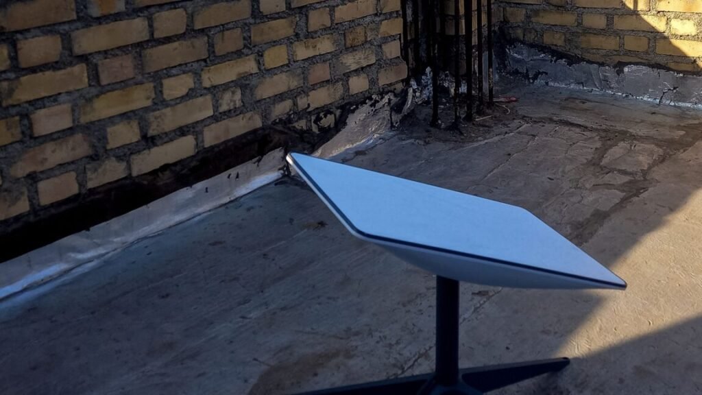 A Starlink satellite dish sitting on top of the upper part of a house in an area enclosed by short brick walls.